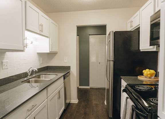 A kitchen with black appliances and white cabinets at Astor Place of Edina Apartments , Edina