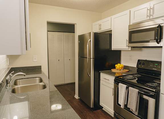 A kitchen with a black refrigerator and stove top oven at Astor Place of Edina Apartments , Edina, MN