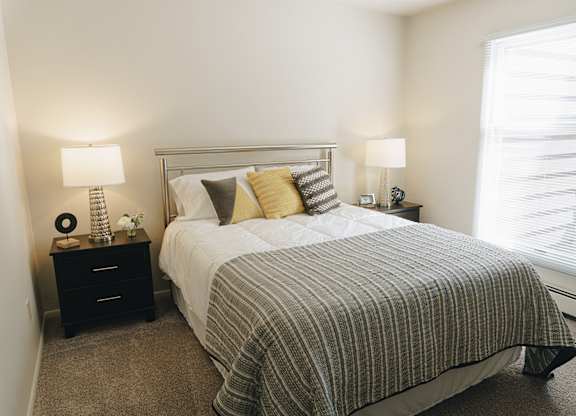 A bedroom with a bed, nightstands, and a window at Astor Place of Edina Apartments , Edina, MN, 55435