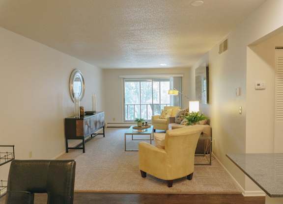 A living room with a yellow chair and a brown rug at Astor Place of Edina Apartments , Edina, 55435