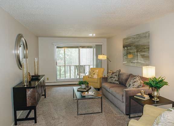 A living room with a couch, coffee table, and a large window at Astor Place of Edina Apartments , Edina