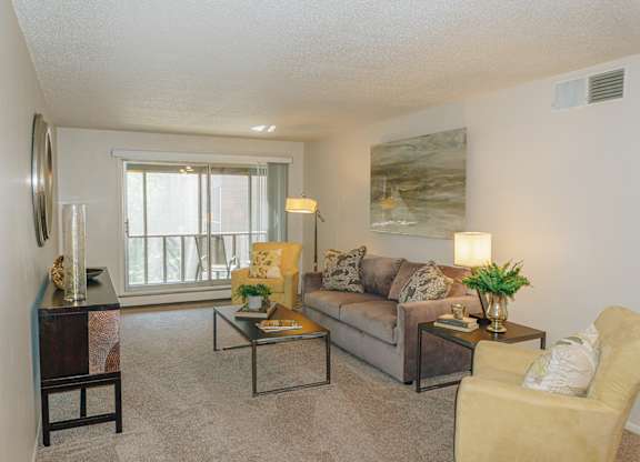 A living room with a couch, chair, and a painting on the wall at Astor Place of Edina Apartments , Edina, Minnesota