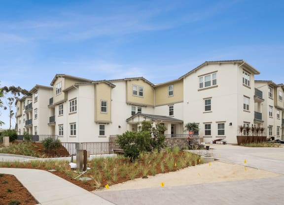 a row of apartment buildings with a sidewalk in front of them at Arrive Los Carneros Apartments, Goleta, CA, 93117