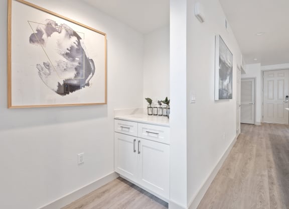 a kitchen with white cabinets and a painting on the wall at Arrive Los Carneros Apartments, Goleta, 93117