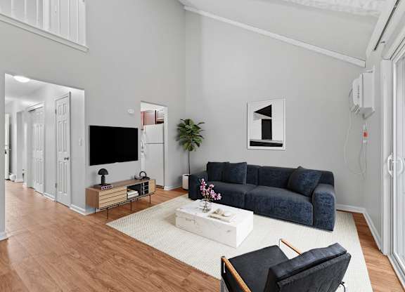 A living room with a blue couch, a white coffee table, and a television.