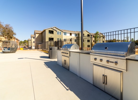 two stainless steel barbecue grills on a patio with apartments in the background at Arrive Paso Robles, Paso Robles