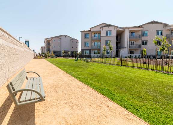 A park with a bench and apartment buildings in the background.