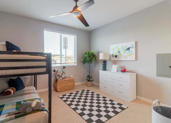 A bedroom with a bed, a ceiling fan, a dresser, and a rug.