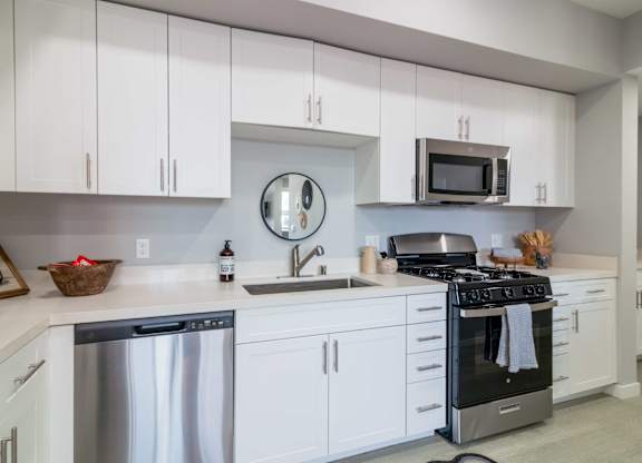 A modern kitchen with white cabinets and stainless steel appliances.