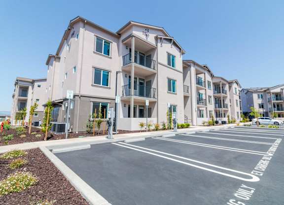 A parking lot in front of apartment buildings with a sign that says