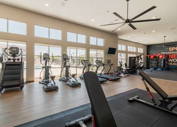 A gym with a variety of exercise equipment including treadmills, stationary bikes, and weight machines.