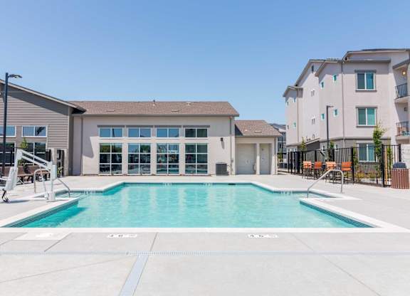 A large swimming pool in front of a building with a clear blue sky above.