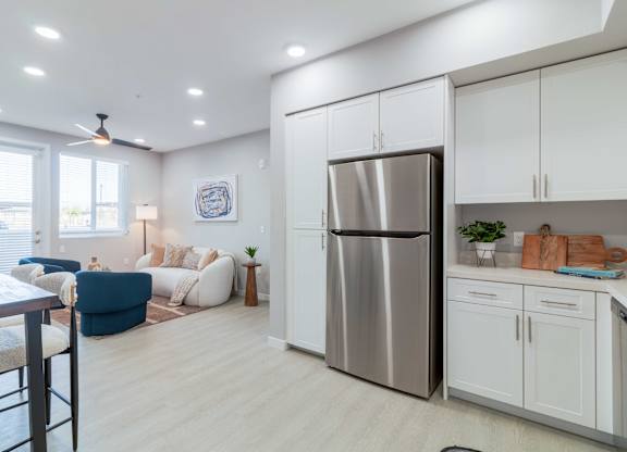 A modern kitchen with a stainless steel refrigerator and white cabinets.