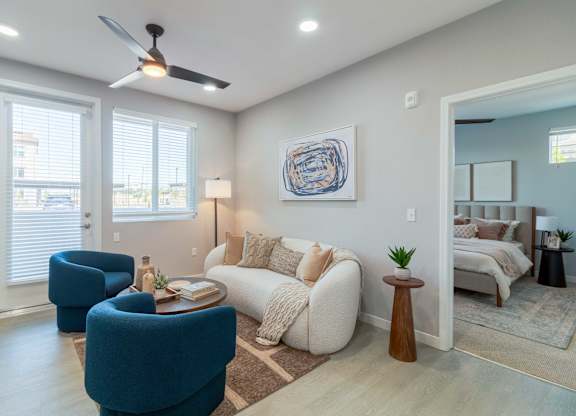 A living room with a blue chair, a white couch, and a ceiling fan.