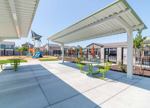 A courtyard sitting area with shade and a playground in the background