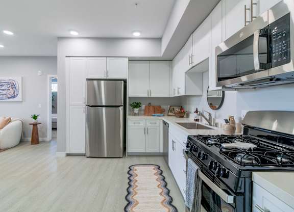 A modern kitchen with a stainless steel refrigerator and a black microwave above the stove.