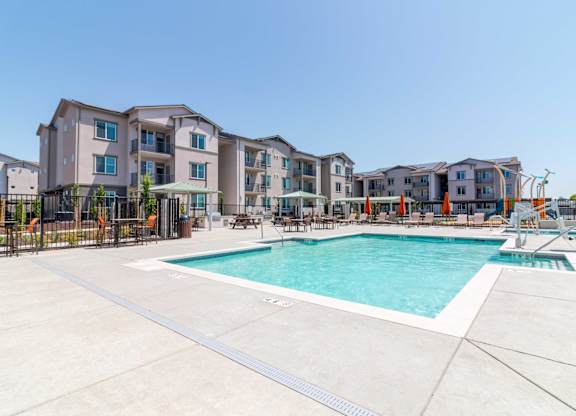 A large swimming pool in front of apartment buildings.