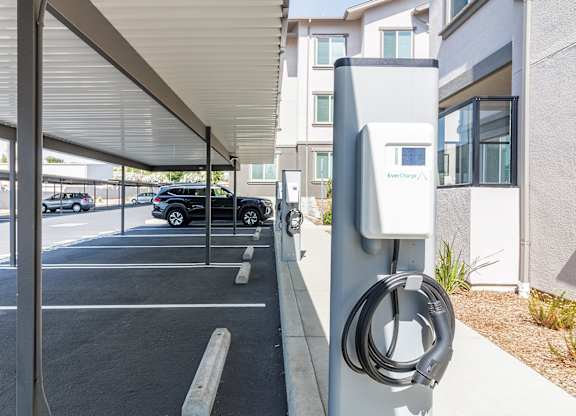 A charging station for electric vehicles is located under a covered parking area.