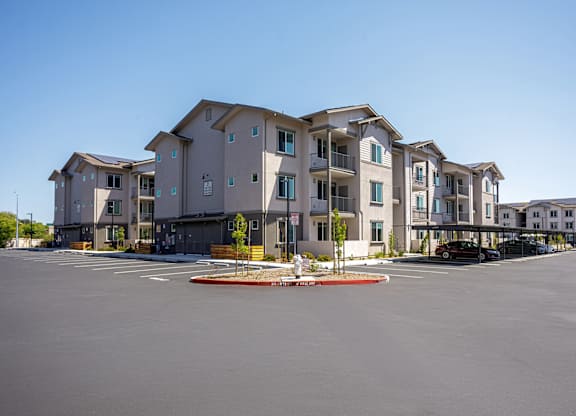 A large apartment building with a parking lot in front of it.
