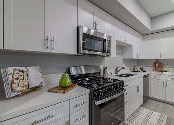 A modern kitchen with a stove, microwave, and oven.
