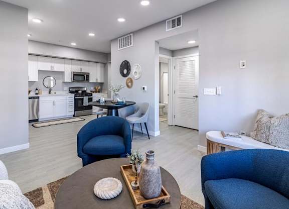 A modern living room with a kitchen in the background.