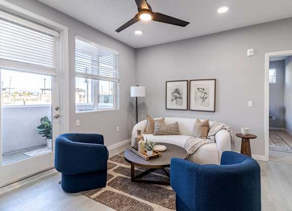 A living room with a blue chair, a white couch, and a ceiling fan.