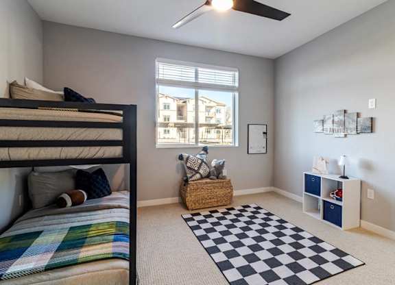A bedroom with a bunk bed and a window overlooking a building.