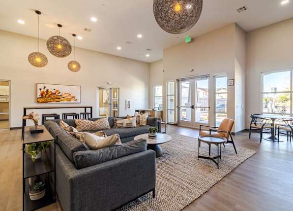 A spacious living room with a grey sofa and a large window.