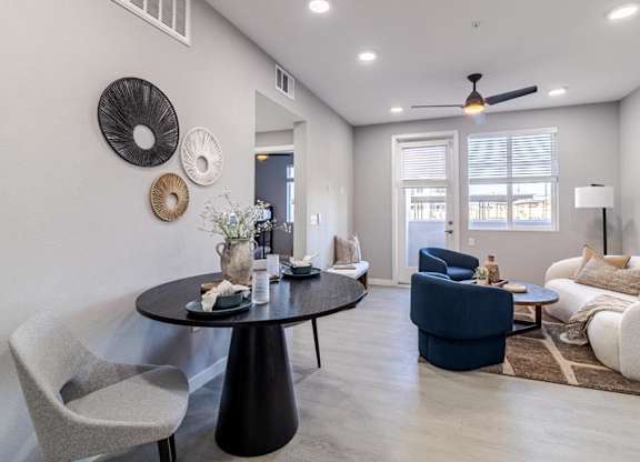 A modern living room with a black table and grey chairs.