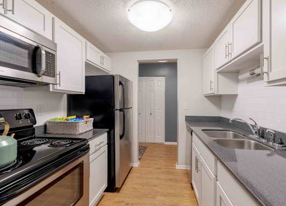 A kitchen with black and white appliances and wooden floors.