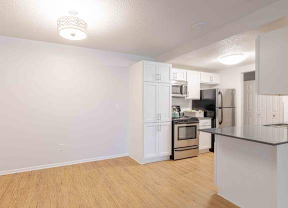 A kitchen with white cabinets and a black countertop.