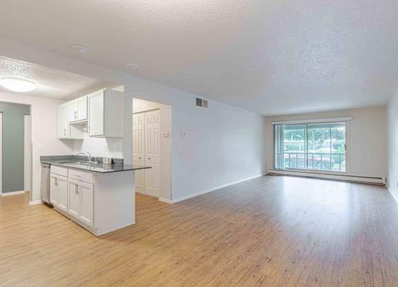 A kitchen with white cabinets and a wooden floor.