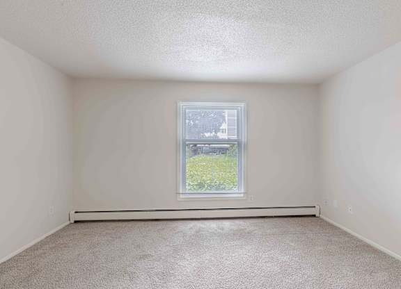 A room with a window and carpeted floor.