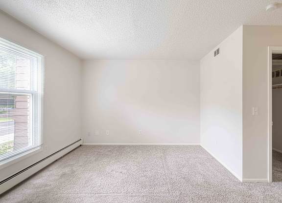 A room with a carpeted floor and a window on the left side.