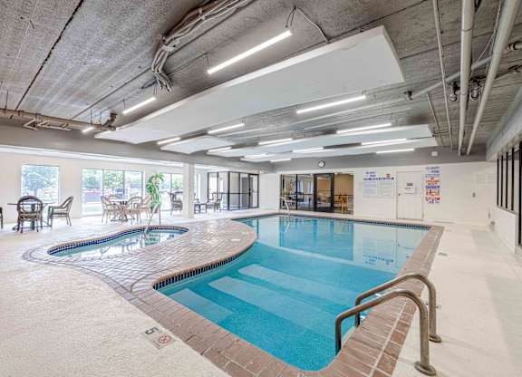 A large indoor swimming pool with a mosaic tile edge and a metal ladder.