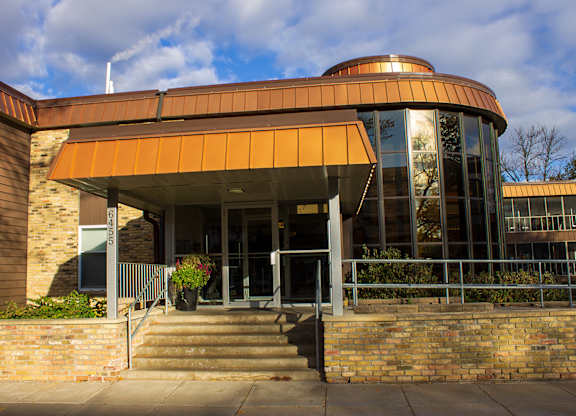 A building with a brown and orange roof and glass windows at Astor Place of Edina Apartments , Edina, MN