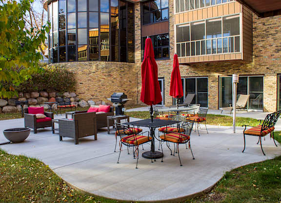 A patio with a table and chairs and umbrellas at Astor Place of Edina Apartments , Edina, MN, 55435