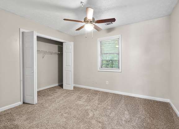 A room with a ceiling fan and a window with blinds.