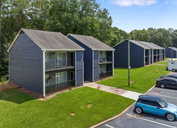 a row of blue buildings with gray roofs and a blue car parked in a parking lot at Alcovy Terrace, Georgia, 30014