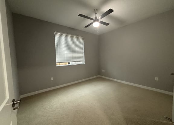 a bedroom with a ceiling fan and a window