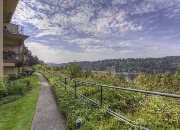 a walkway next to a building with a view of a river and trees at Overlook at the Willamette, Milwaukie, OR ?