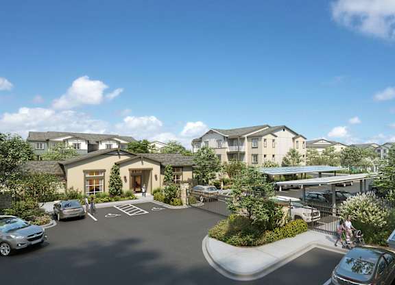 A sunny day at a residential complex with cars parked and solar panels on the roof.
