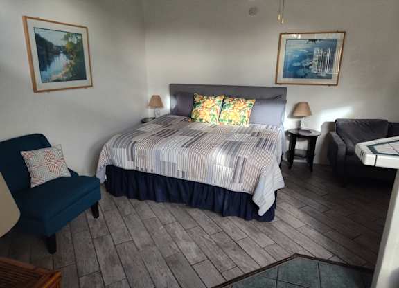A bedroom with a bed, chair, and two lamps at Salinas Sunset Apartments, Salinas, 93907