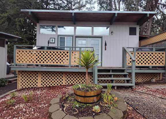 Cabin with a wooden deck and a potted plant in front at Salinas Sunset Apartments, California, 93907