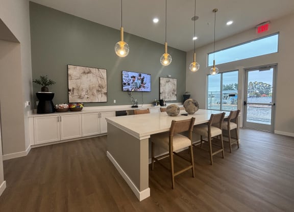 Clubhouse kitchen with a large island with chairs and a tv