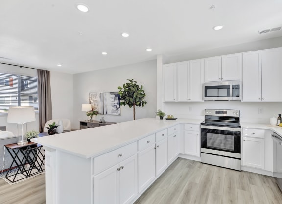 an open kitchen with white cabinets and a white counter top