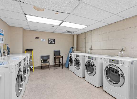 A laundry room with washing machines and a chair at The Exeter Apartments, Seattle, 98101