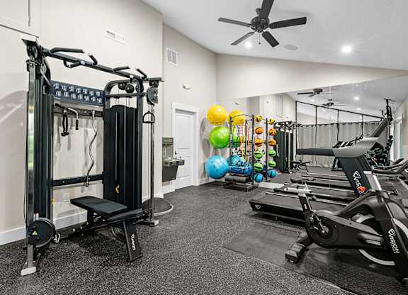 A gym with a variety of equipment including treadmills, weights, and a bench.