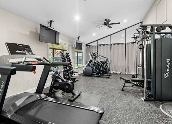 A gym with treadmills, exercise bikes, and other equipment.