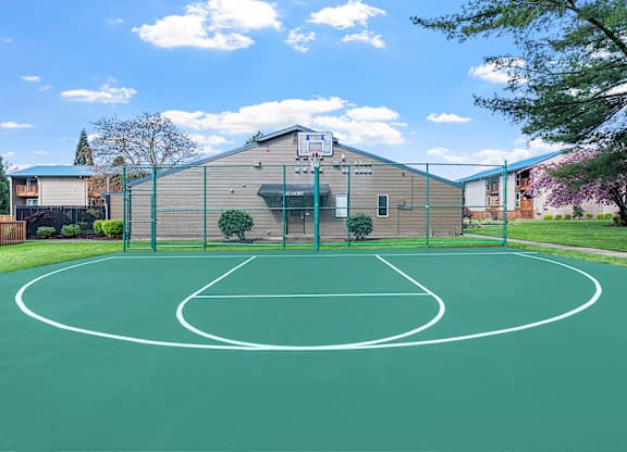 A basketball court with a green surface and white lines.